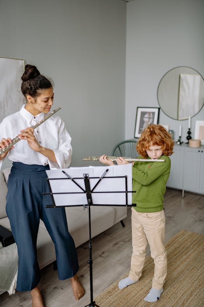 Home A child learning to play the flute with a teacher at home, focused on music sheets.